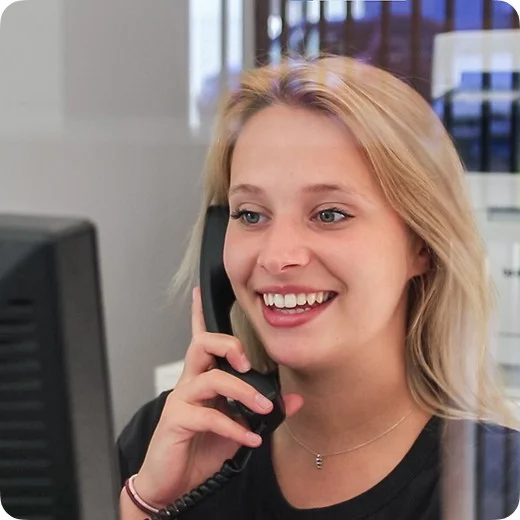 A person at a desk speaking on the phone beside a computer